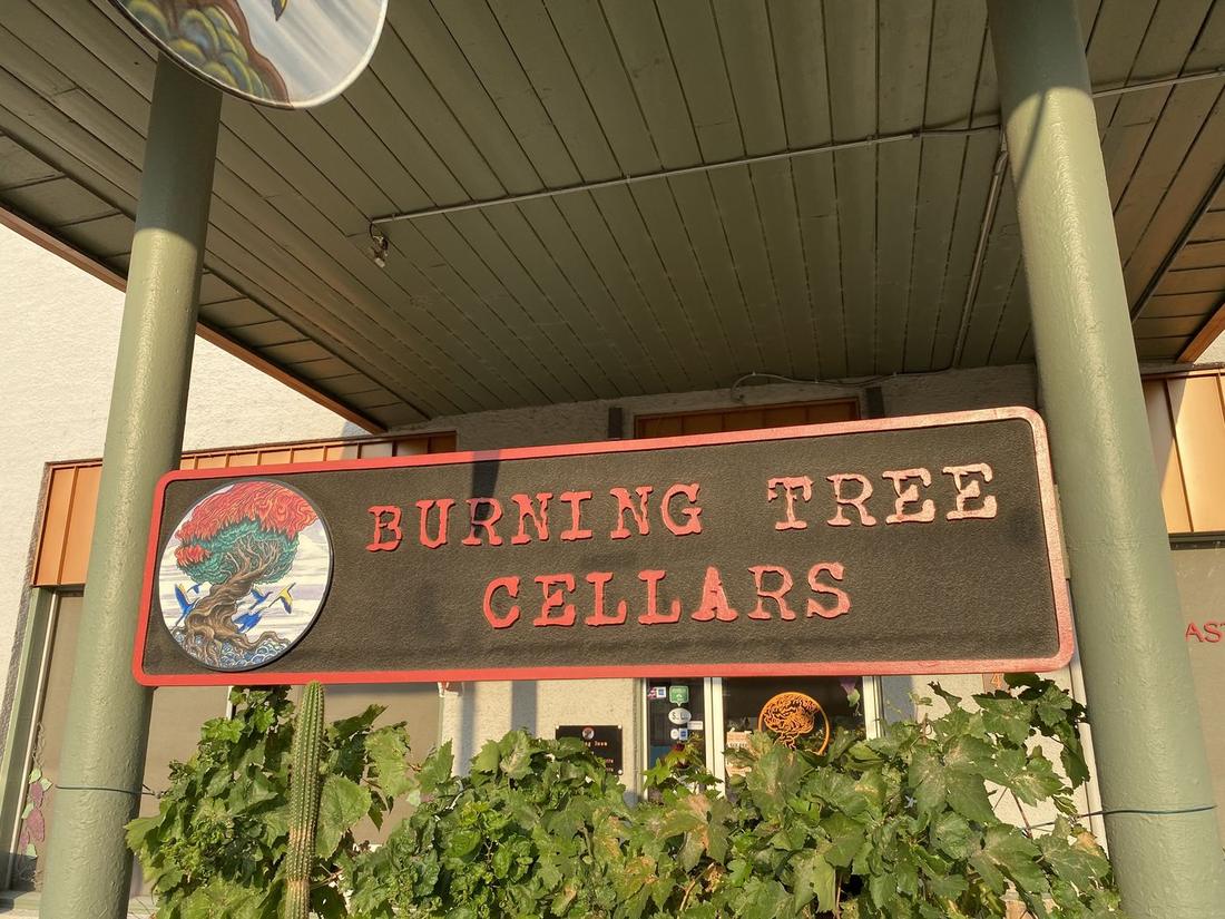 A wine cellar's hand-painted sign under a porch roof in Old Town Cottonwood