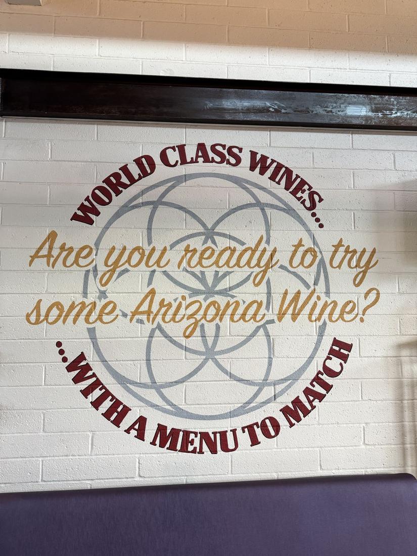 A painted wall in a Cottonwood wine bar that reads, Are you ready to try some Arizona wine, with a menu to match