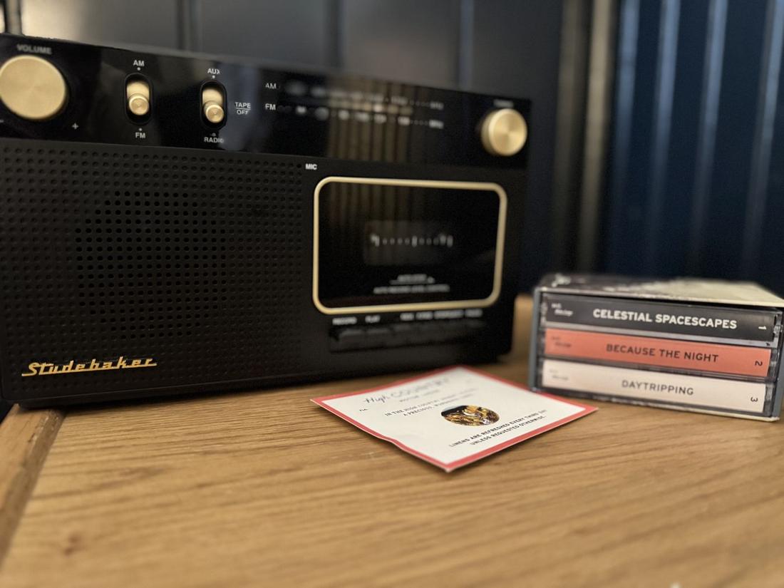 A vintage-style radio and a stack of cassette tapes on a wooden table in a Flagstaff hotel room