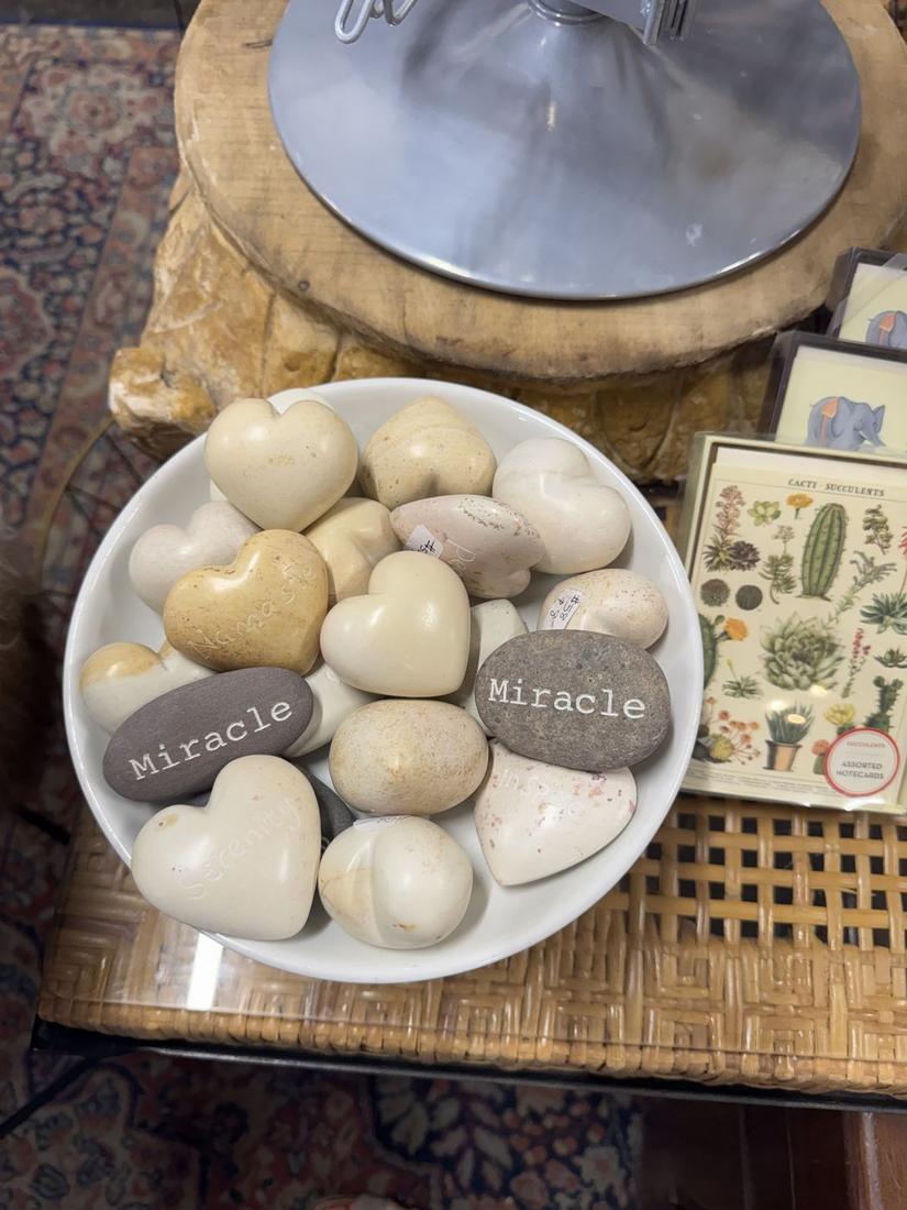 A bowl of heart-shaped stones and botanical cards on a shop table in downtown Prescott