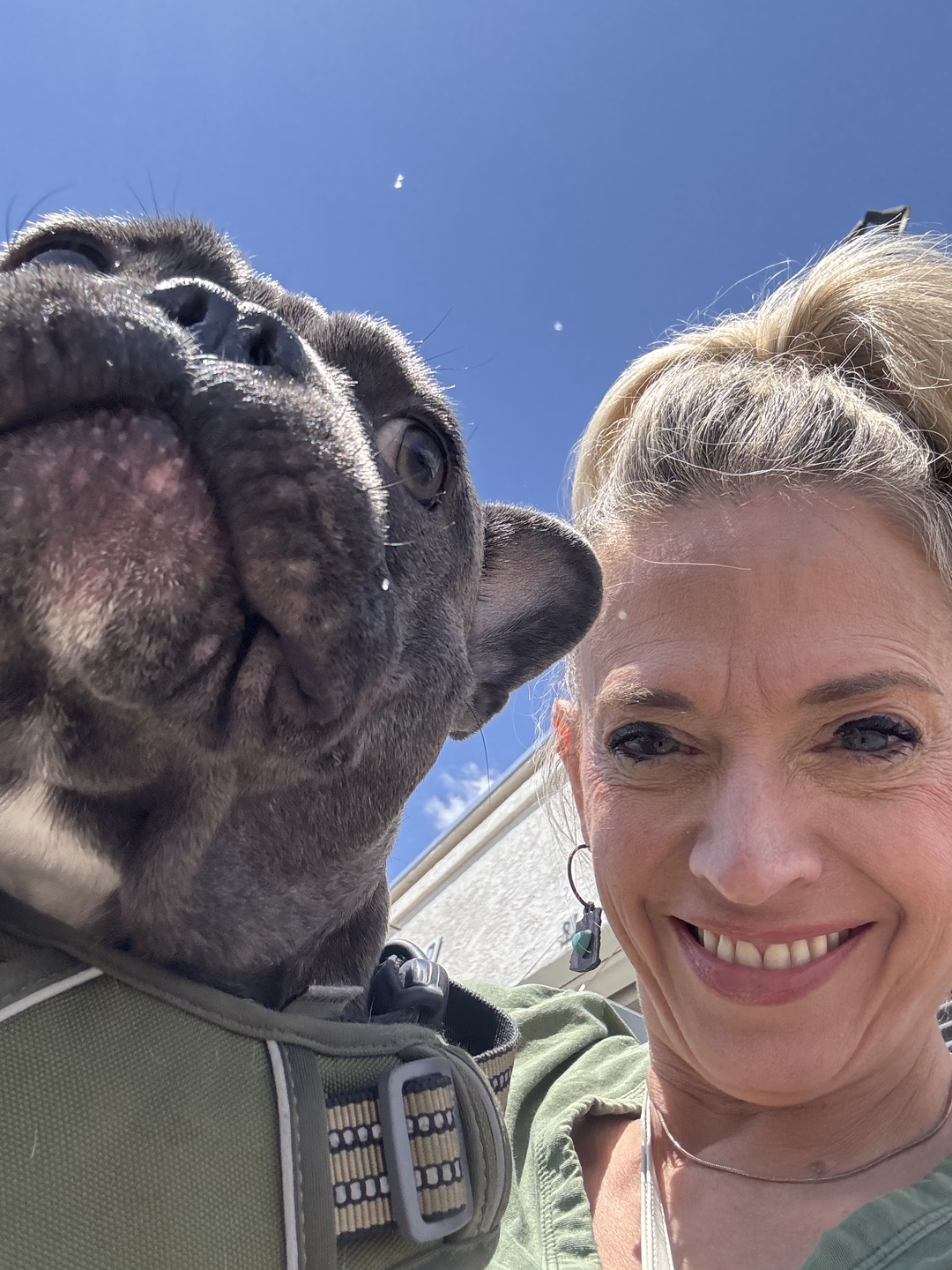 Gina and Dexter outdoors under a bright blue Arizona sky, both smiling into the camera.